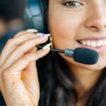 Close-up of a cheerful woman with headphones, engaged in a customer service role.